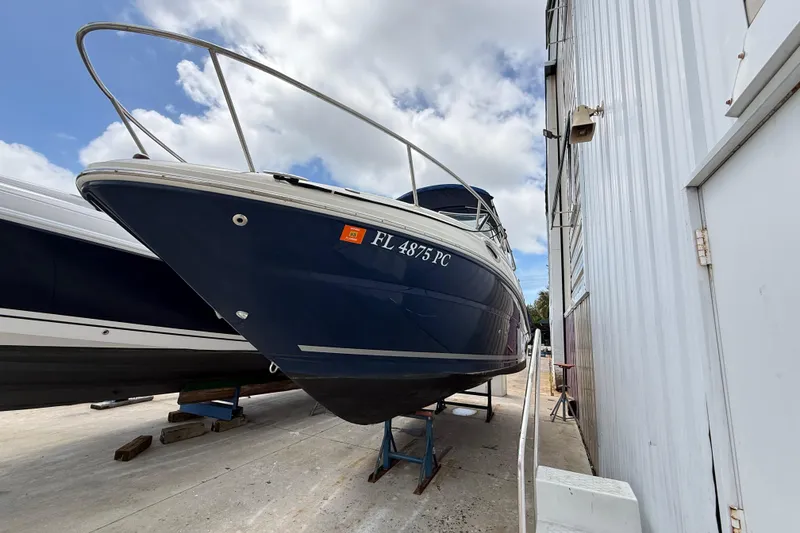 The Image of 2010 Sea Ray 240 Sundancer boat on dry dock beside a building. - 0