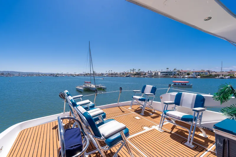 Slide: The Image of 2001 Bayliner 5788 Pilot House Motoryacht deck with seating, overlooking serene waterfront. - 16