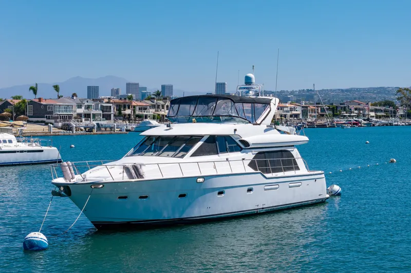 The Image of 2001 Bayliner 5788 Pilot House Motoryacht docked in a scenic marina. - 0
