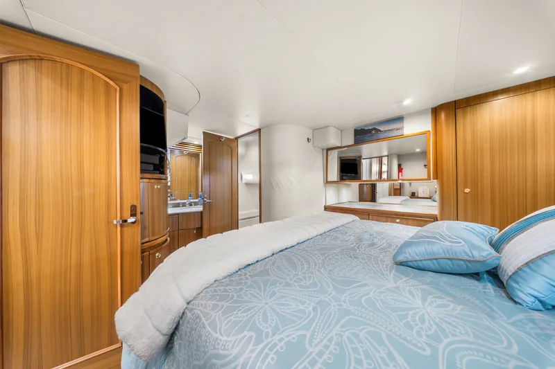 Slide: The Image of Luxurious bedroom interior of 2001 Bayliner 5788 Pilot House Motoryacht with wood accents and plush bedding. - 33