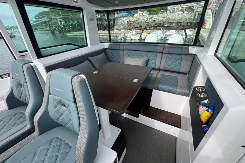 Slide: The Image of 2024 Axopar 37 XC Cross Cabin interior with seating and table, dockside view. - 19