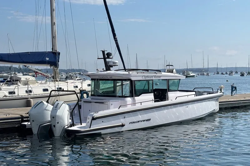 Slide: The Image of 2024 Axopar 37 XC Cross Cabin docked at a marina with twin outboard engines. - 2