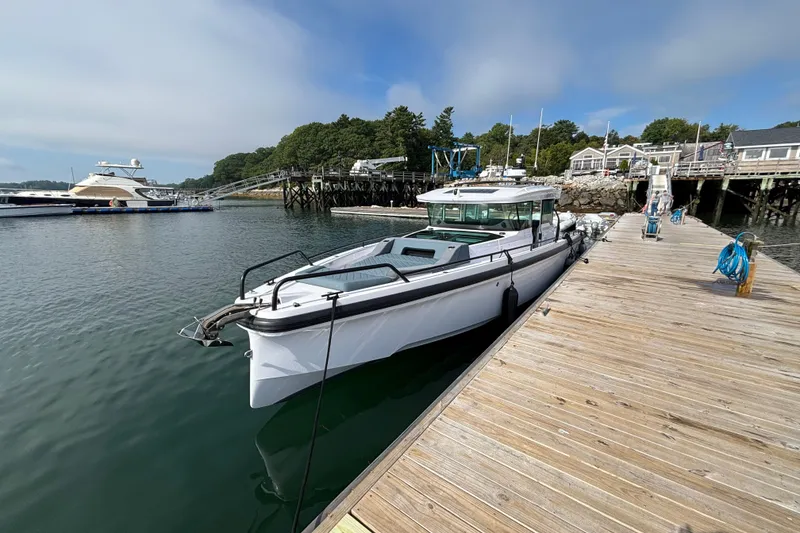 Slide: The Image of 2024 Axopar 37 XC Cross Cabin docked at a marina, surrounded by calm waters. - 5