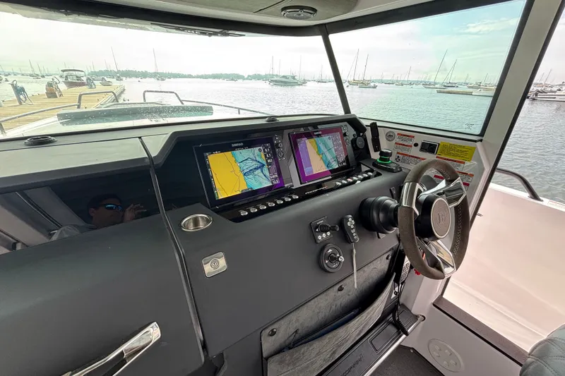 Slide: The Image of 2024 Axopar 37 XC Cross Cabin helm with navigation screens and steering wheel. - 17