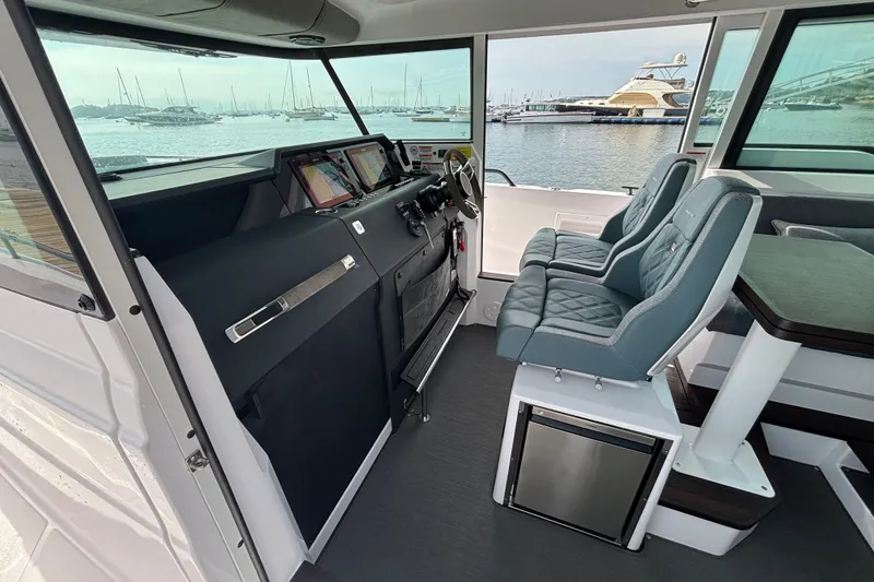 Slide: The Image of 2024 Axopar 37 XC Cross Cabin interior with modern dashboard and seating, overlooking marina. - 15