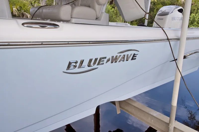 Slide: The Image of 2021 Blue Wave 2800 Makaira boat with Suzuki engine, docked near lush greenery. - 6