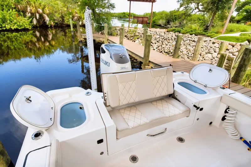 Slide: The Image of 2021 Blue Wave 2800 Makaira boat interior with seating and Suzuki engine by a dock. - 12
