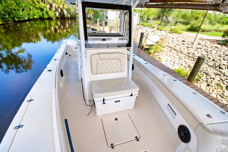 Slide: The Image of 2021 Blue Wave 2800 Makaira boat interior with seating and storage, docked by a serene river. - 42