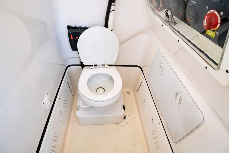 Slide: The Image of Boat interior with a compact marine toilet in a 2021 Blue Wave 2800 Makaira model. - 56
