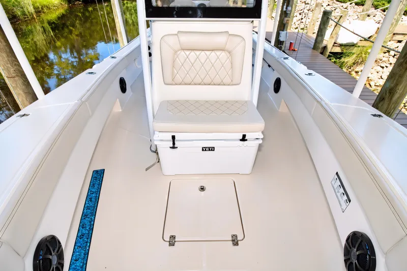 Slide: The Image of The image shows the deck of a 2021 Blue Wave 2800 Makaira boat with a bench seat and cooler. - 47