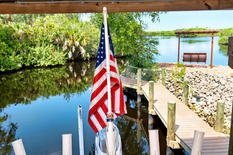 Slide: The Image of American flag on a 2021 Blue Wave 2800 Makaira boat docked by a scenic river. - 59