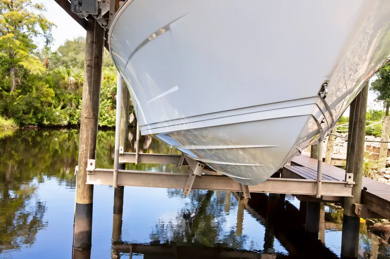 Slide: The Image of 2021 Blue Wave 2800 Makaira boat on lift by a serene riverbank. - 8