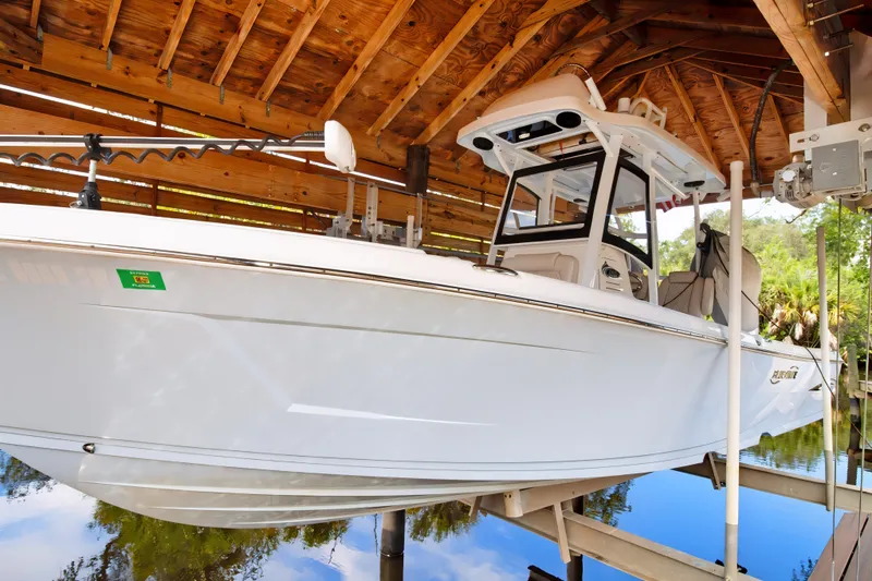 Slide: The Image of 2021 Blue Wave 2800 Makaira boat docked under wooden shelter. - 2