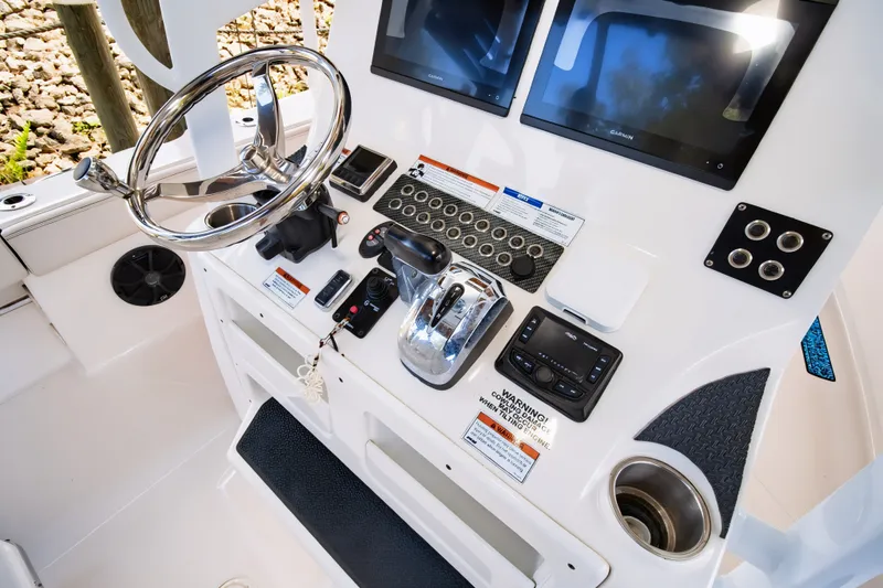 Slide: The Image of 2021 Blue Wave 2800 Makaira boat console with steering wheel, controls, and dual screens. - 36