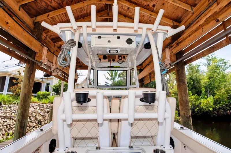 Slide: The Image of 2021 Blue Wave 2800 Makaira boat under wooden dock, showcasing interior and fishing rod holders. - 24