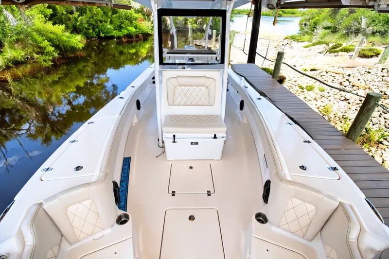 Slide: The Image of 2021 Blue Wave 2800 Makaira boat interior with seating, docked by a scenic river. - 46