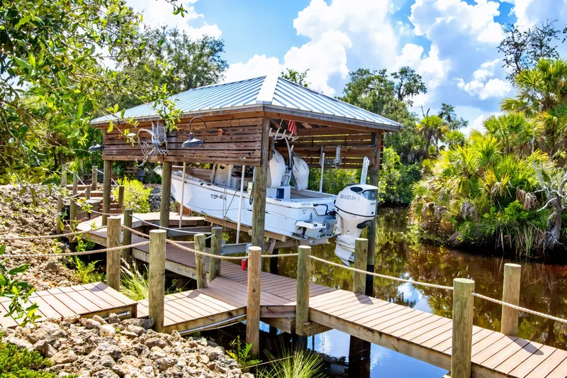 Slide: The Image of Boat docked under wooden shelter, Blue Wave 2800 Makaira, 2021 model, surrounded by lush greenery. - 10