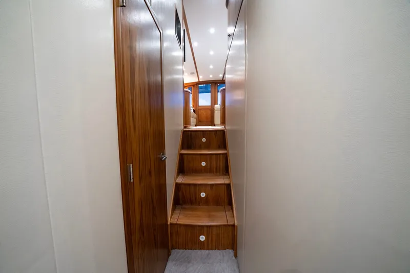 Slide: The Image of Wooden stairs in a boat with white walls and ceiling lights. - 38
