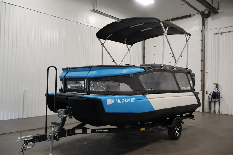 Slide: The Image of 2023 Sea-Doo Switch 16 pontoon boat in a garage, featuring a blue and black design. - 28