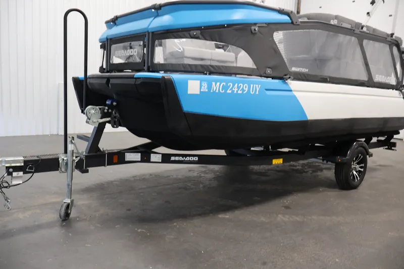 Slide: The Image of 2023 Sea-Doo Switch 16 on trailer, blue and white design, indoor setting. - 31