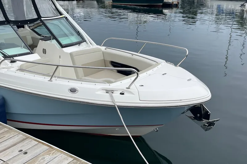 Slide: The Image of 2023 Boston Whaler 240 Vantage boat docked in calm marina waters. - 10