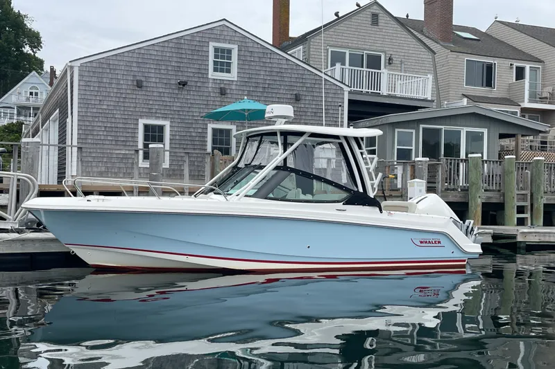 Slide: The Image of 2023 Boston Whaler 240 Vantage boat docked near waterfront homes. - 26