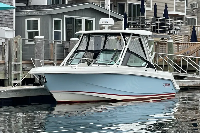 Slide: The Image of 2023 Boston Whaler 240 Vantage boat docked by waterfront homes. - 23