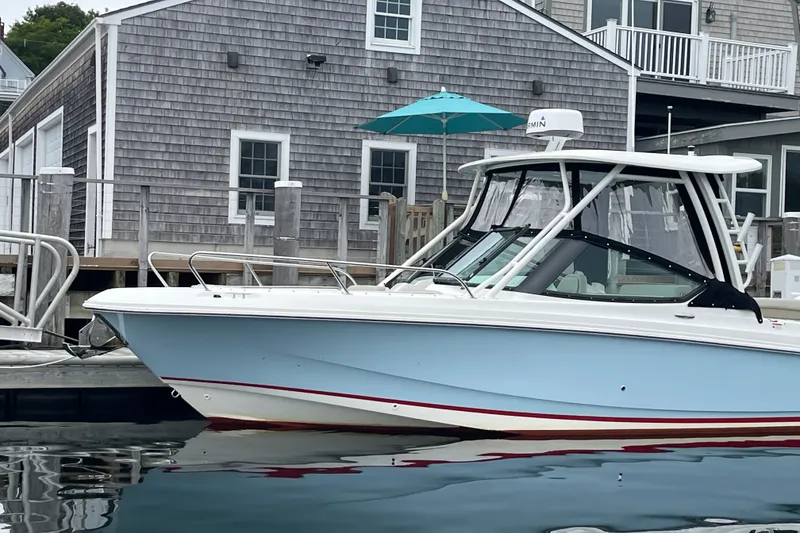 Slide: The Image of 2023 Boston Whaler 240 Vantage boat docked near a wooden building. - 25