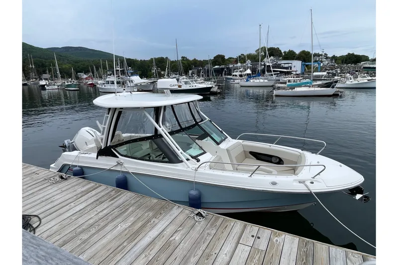 Slide: The Image of 2023 Boston Whaler 240 Vantage boat docked in a marina with other vessels. - 2