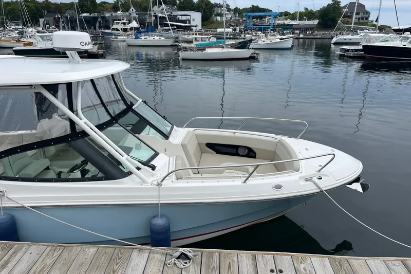Slide: The Image of 2023 Boston Whaler 240 Vantage docked in a marina, surrounded by other boats. - 7