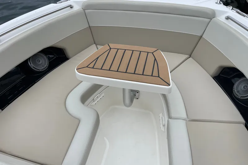 Slide: The Image of 2023 Boston Whaler 240 Vantage boat interior with cushioned seating and wooden table. - 65