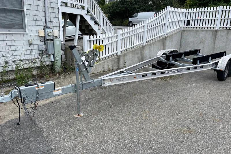 Slide: The Image of Trailer for 2023 Boston Whaler 240 Vantage parked on pavement near white fence. - 82