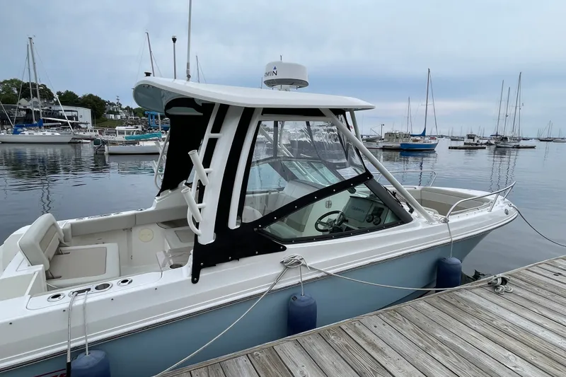 Slide: The Image of 2023 Boston Whaler 240 Vantage docked at a marina with sailboats in the background. - 21