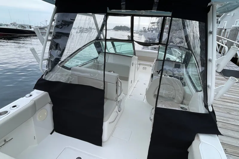 Slide: The Image of 2023 Boston Whaler 240 Vantage boat interior with protective covers docked by the water. - 78