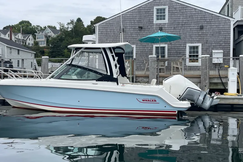 Slide: The Image of 2023 Boston Whaler 240 Vantage boat docked by a waterfront building. - 1