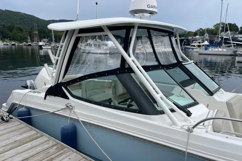 Slide: The Image of 2023 Boston Whaler 240 Vantage docked at a marina with scenic background. - 13