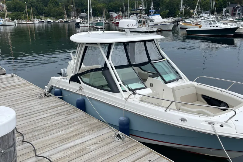 Slide: The Image of 2023 Boston Whaler 240 Vantage docked in a scenic marina setting. - 8