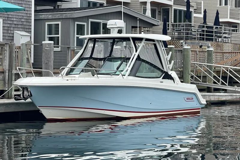 Slide: The Image of 2023 Boston Whaler 240 Vantage boat docked near waterfront homes. - 24