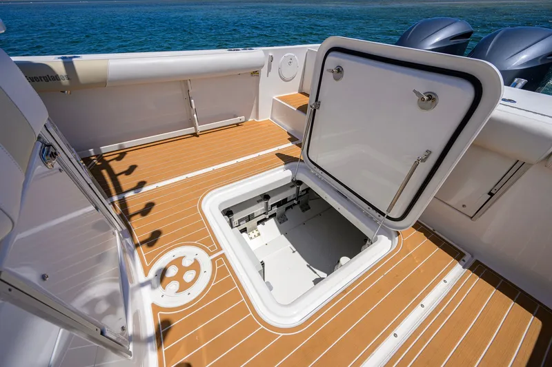 Slide: The Image of 2018 Everglades 355 Center Console boat with open storage hatch on teak deck. - 43
