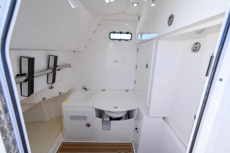 Slide: The Image of Interior of 2018 Everglades 355 Center Console boat, featuring a compact bathroom. - 50