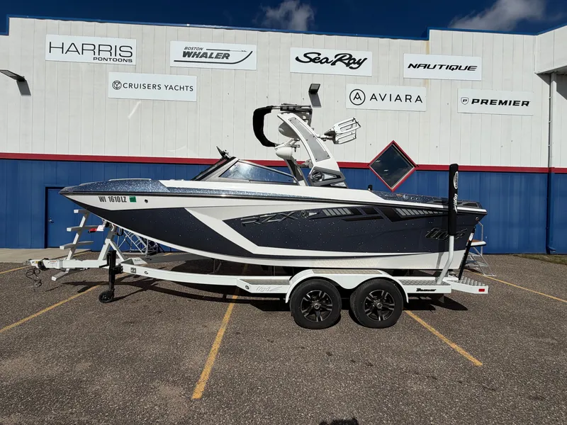 Slide: The Image of 2019 Tigé 20RZX in front of a building with boat brand logos. - 0