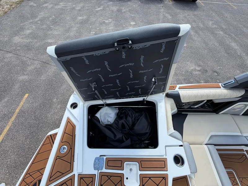 Slide: The Image of An open storage compartment on a 2019 Tigé 20RZX boat with cushioned seats and wood flooring. - 18