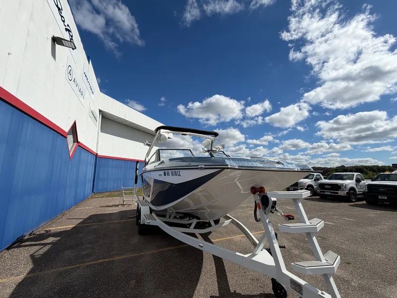 Slide: The Image of A 2019 Tigé 20RZX boat on a trailer in front of a building under a blue sky. - 2