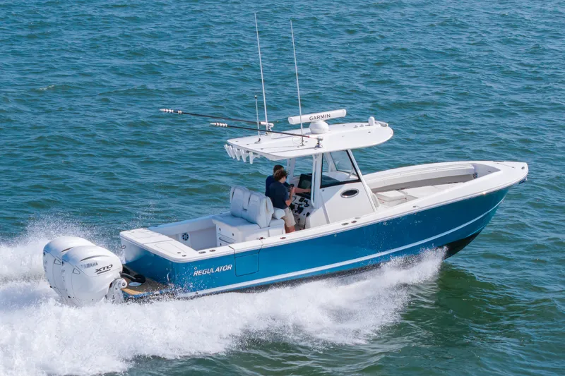 Slide: The Image of A 2024 Regulator 31 boat speeds across the water. It features a blue hull design. - 2