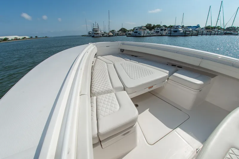 Slide: The Image of The image shows the bow of a 2024 Regulator 31 boat with cushioned seating and a clear view of the marina. - 16