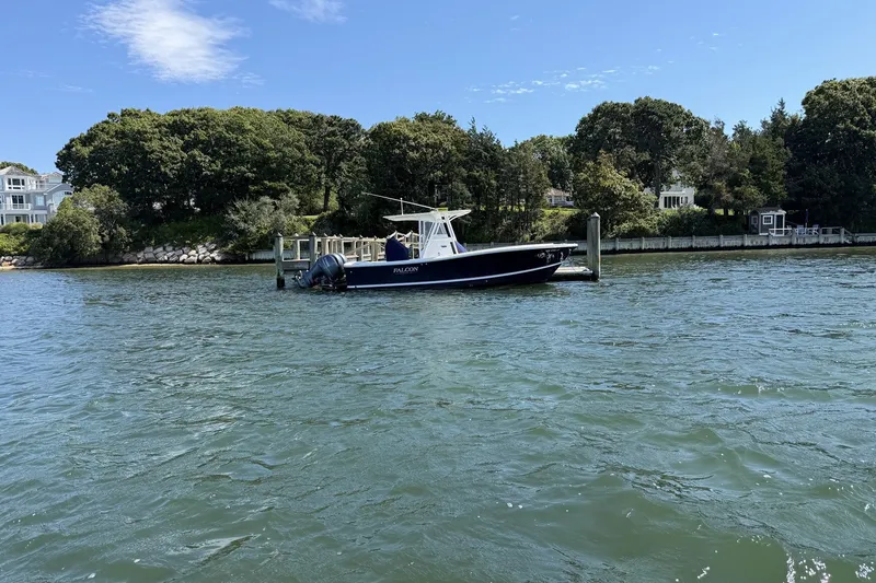 Slide: The Image of 2015 Regulator 25 boat docked by a scenic waterfront with lush greenery. - 6