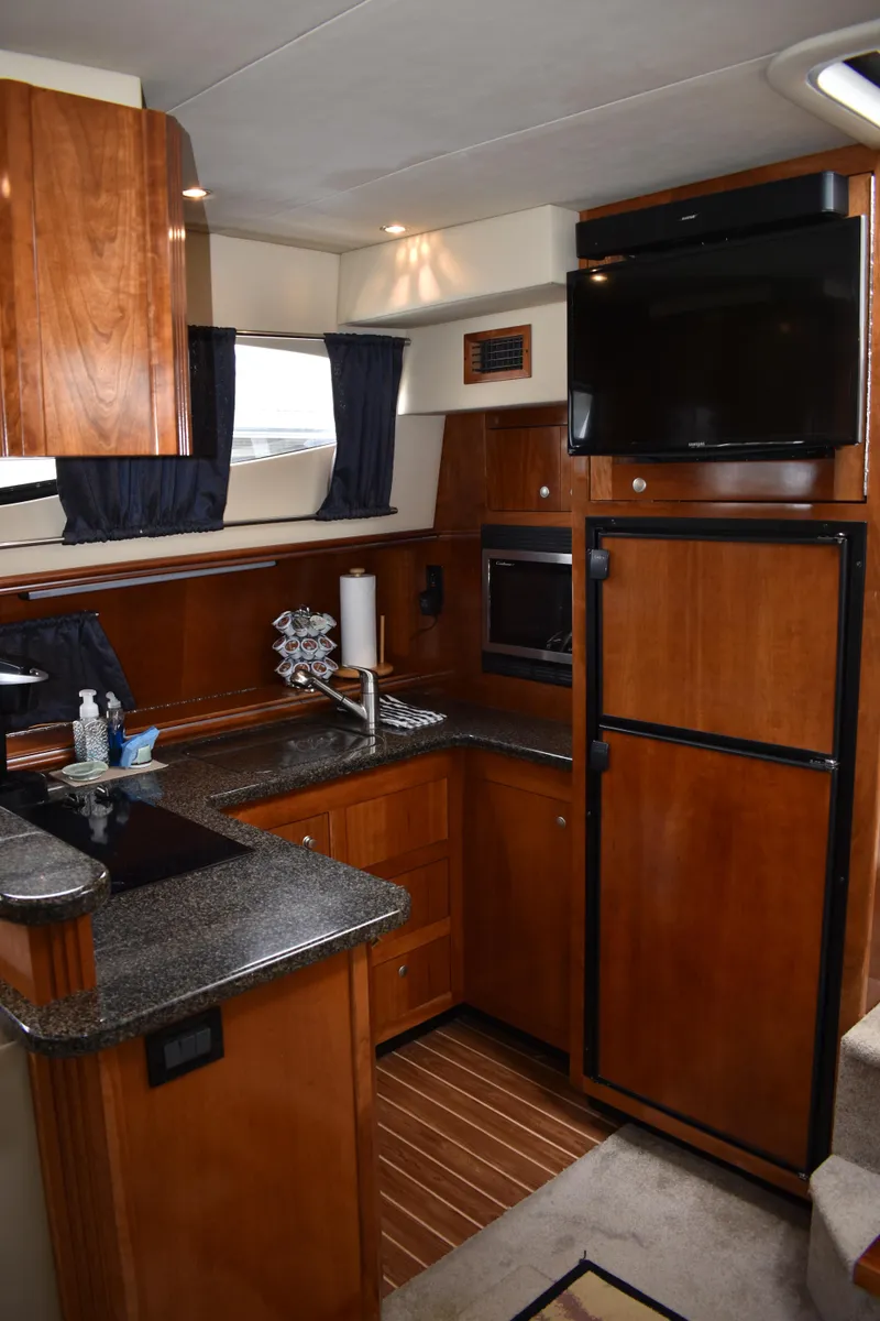 Slide: The Image of Die Küche der 2006er Cruisers Yachts 415 Express Motoryacht verfügt über Holzschränke, einen Kühlschrank und eine Mikrowelle. - 8