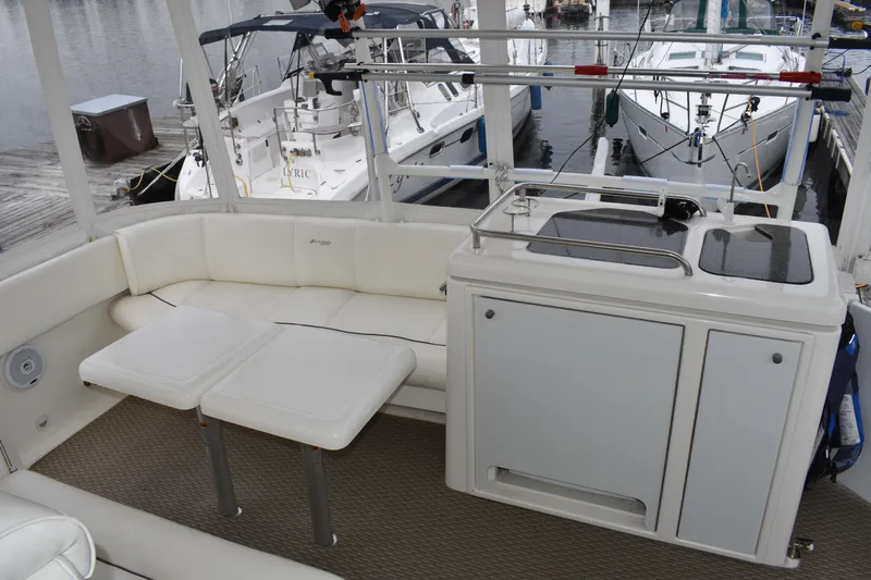 Slide: The Image of Das Bild zeigt das Cockpit einer Cruisers Yachts 415 Express Motoryacht von 2006 mit weißen Sitzgelegenheiten und einer kleinen Küchenzeile. - 2