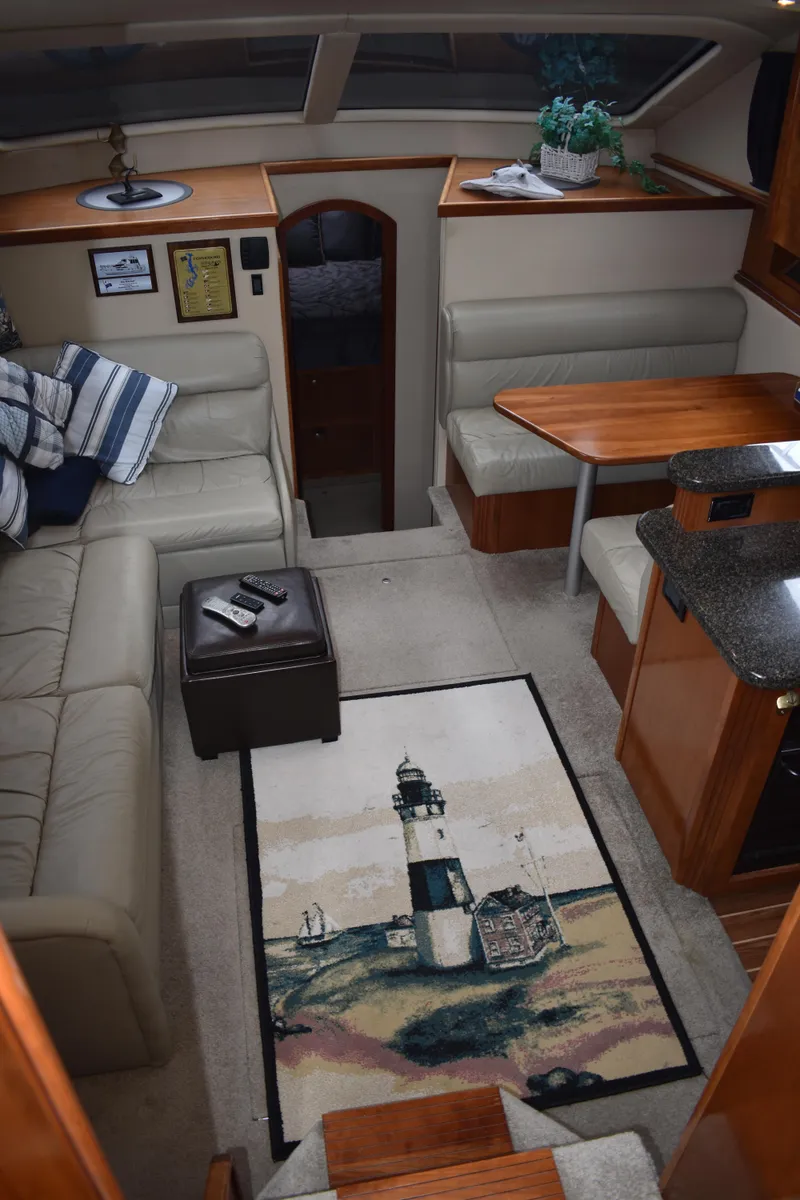 Slide: The Image of Innenraum der 2006 Cruisers Yachts 415 Express Motoryacht mit gemütlichem Sofa und Teppich mit Leuchtturmmotiv. - 11
