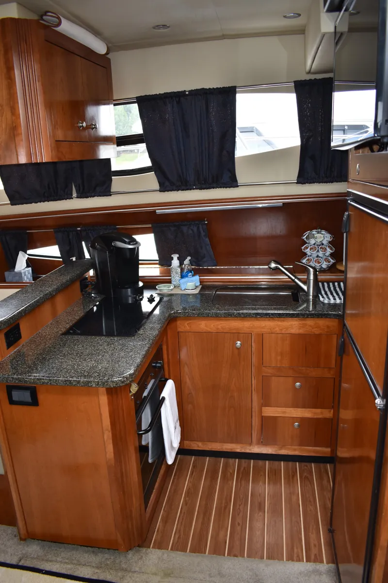 Slide: The Image of Die Küche der Cruisers Yachts 415 Express Motoryacht von 2006 zeigt Holzschränke und eine Arbeitsplatte. - 10